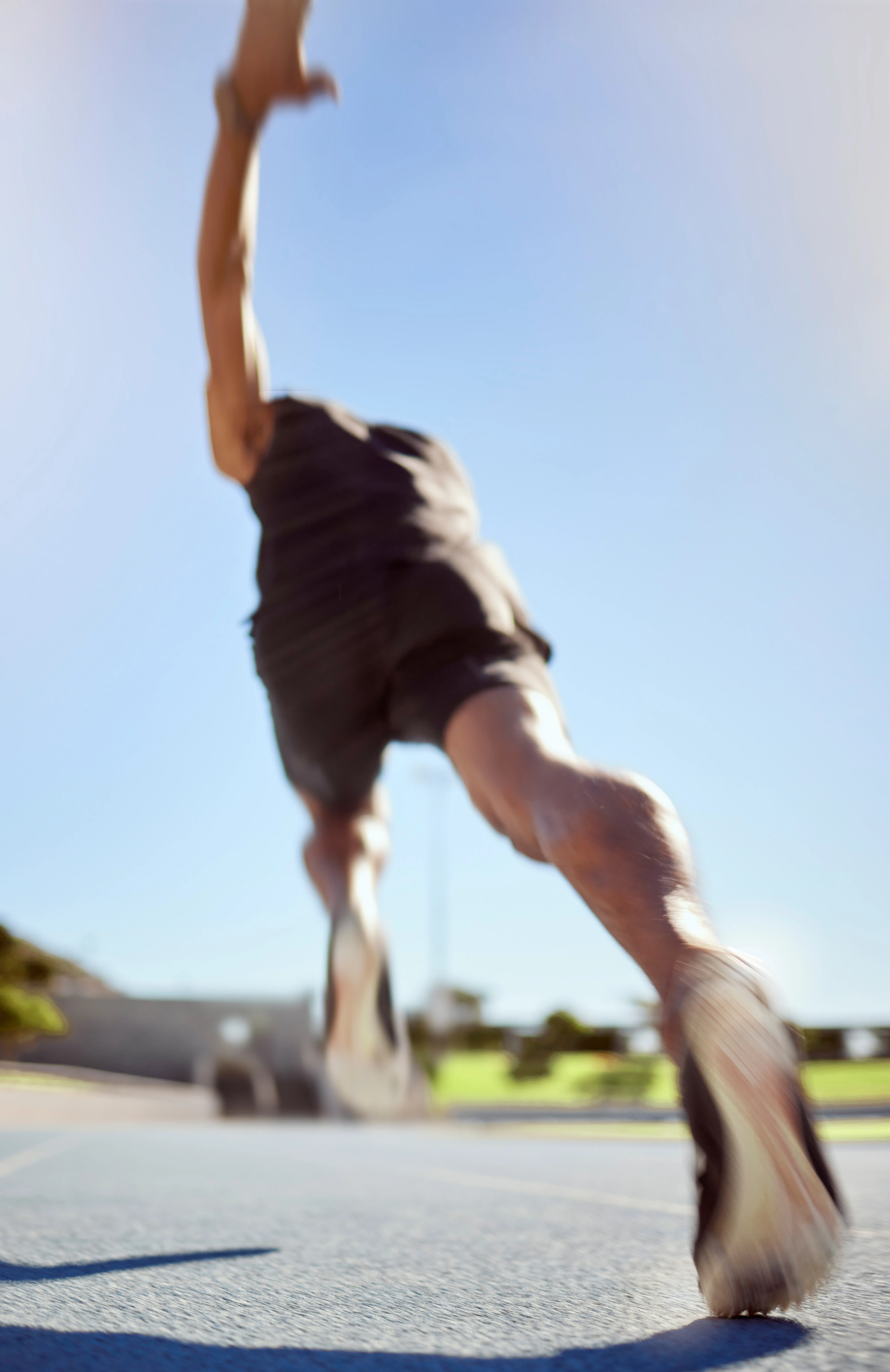A runner accelerating on an outdoor track, captured with motion blur