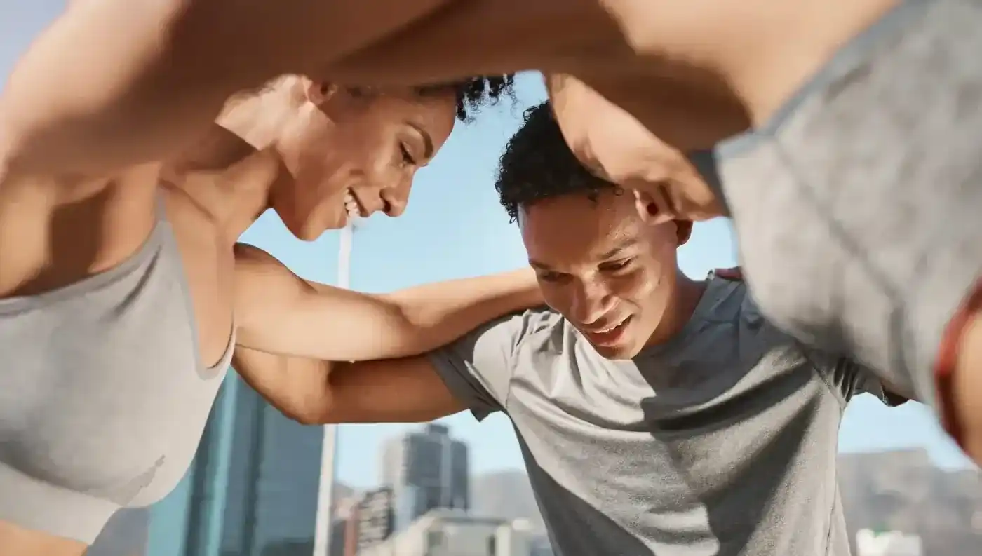 Two people stretching together outdoors with a city skyline behind them